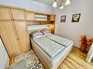 um pequeno quarto com uma cama e armários de madeira em Tavirózsa 1A em Hévíz