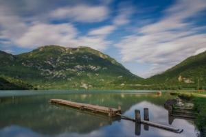 a reflection of a dock in a lake with mountains at da Paola monolocale in Osoppo
