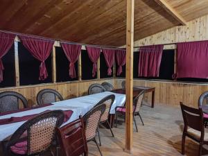 Shaa-boto في Alamedin: غرفة طعام مع طاولات وكراسي وستائر حمراء