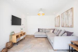 a white living room with a couch and a tv at Lythwood House in Gloucester