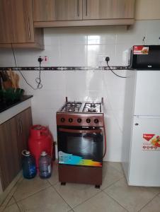 a small kitchen with a stove and a refrigerator at Annbree's apartment in Ruiru