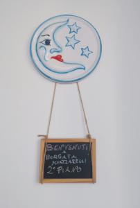 un panneau avec une femme sur la lune et un tableau noir dans l'établissement Borgata Mazzarelli 2, à Marina di Ragusa