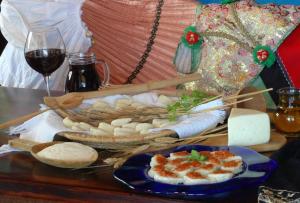 una mesa con un plato de comida y una copa de vino en B&B La Torre, en Loceri