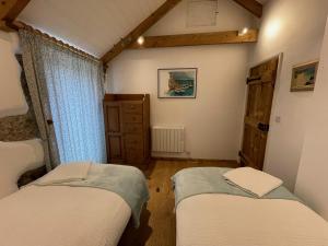 1 dormitorio con 2 camas individuales y vestidor en Trengothal Barn, en Porthcurno