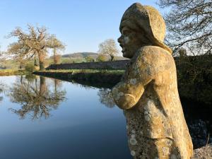 Una statua di una donna in piedi accanto a un corpo d'acqua. di Domaine de la Motte-Basse a Le Gouray