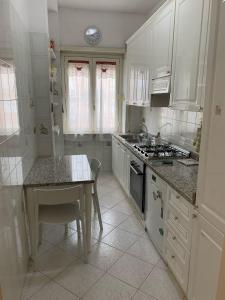 cocina con armarios blancos, mesa y fregadero en GRAZIOSO MONOLOCALE OSTIA ROMA, en Lido di Ostia