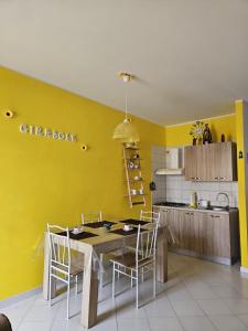 サン・ヴィート・ロ・カーポにあるAppartamento Girasoleの黄色の壁のキッチン(テーブル、椅子付)