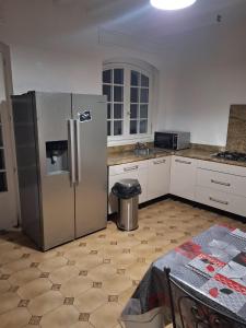 uma cozinha com um frigorífico de aço inoxidável e uma mesa em Jolie demeure proche stade de France em Drancy