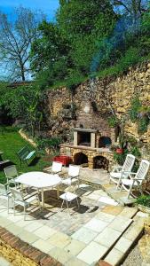 a picnic table and chairs in front of a stone fireplace at Impérial in Puy-lʼÉvêque