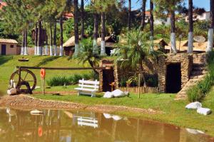 a house with a watermill and a bench next to a pond at Park Hotel Modelo in Pinhalzinho