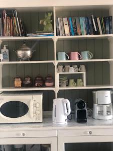 a kitchen shelf with a microwave and cups and books at Sunset Villa with swimming pool at Tzia in Ligia