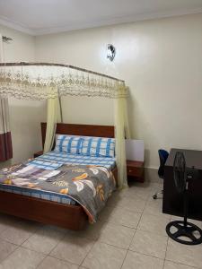 um quarto com uma cama de dossel e uma secretária em MiniPalais Bukoto em Kampala