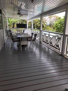 eine Holzterrasse mit einem Tisch und Stühlen darauf in der Unterkunft Taravao Belvedere maison 3ch calme avc Piscine+2 bungalow 15 min Teahupoo wave in Tohautu