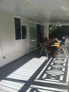 eine Veranda mit einem Tisch und Stühlen auf einem Haus in der Unterkunft Taravao Belvedere maison 3ch calme avc Piscine+2 bungalow 15 min Teahupoo wave in Tohautu