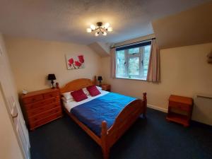 a bedroom with a wooden bed with red pillows and a window at Sue's Cottage. in Symonds Yat