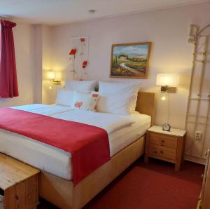 - une chambre avec un grand lit et une couverture rouge dans l'établissement Logis L Auberge Gutshof, à Bischofswerda