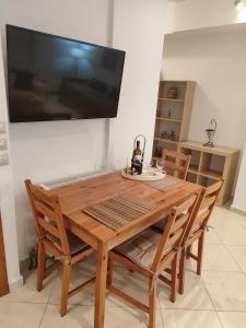 a wooden table with chairs and a television on a wall at Klio's apartment in Lávrion