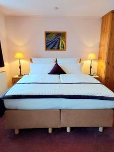 uma cama grande num quarto com duas lâmpadas em Logis L Auberge Gutshof em Bischofswerda