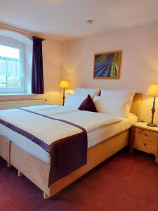 a bedroom with a large bed with two lamps at Logis L Auberge Gutshof in Bischofswerda