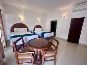 InHouse Select Hacienda Tres Rios في كولياكان: غرفة بسريرين وطاولة وكراسي