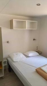 Un dormitorio con una cama blanca con dos almohadas. en Mobil home 4/6 personnes Camping les dunes - les Conches, en Longeville-sur-Mer 5 fotos más