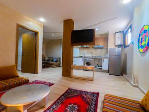 een woonkamer met een bank, een tafel en een koelkast bij Cozy Tamraght 1 Bedroom apartement in Tamraght Ouzdar