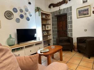 a living room with a tv and a table at Casa de pueblo con merendero y chimenea. in Viguera