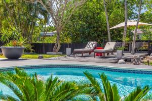 een zwembad met 2 stoelen en een parasol bij Entire Villa, North Miami Beach with pool on canal! in Miami