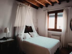 1 dormitorio con 1 cama blanca con dosel en Apartamentos Turisticos La vida de antes, en Consuegra