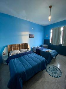 two beds in a room with blue walls at Pousada Alto da Prainha in Rio de Janeiro