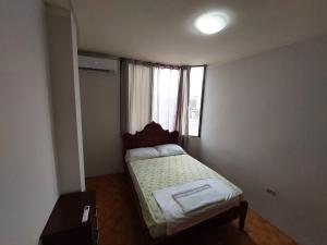 a small bedroom with a bed and a window at Departamentos de la Costa in Machala