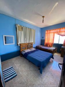 - une chambre avec des murs bleus, un lit et une fenêtre dans l'établissement Pousada Alto da Prainha, à Rio de Janeiro