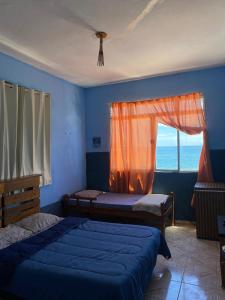 a bedroom with two beds and a window with the ocean at Pousada Alto da Prainha in Rio de Janeiro