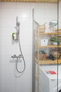 een douche in een badkamer met witte tegels bij Cozy 1-bed super flat, 20 min to Helsinki/Airport in Vantaa
