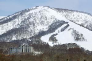a mountain covered in snow with a building on it at One Niseko Resort Towers in Niseko