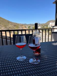 two wine glasses sitting on a table with a bottle of wine at El Valle Golf Resort in Baños y Mendigo