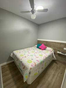 1 dormitorio pequeño con 1 cama con manta de flores en Apartamento Playa Algaida, en Sitio de Calahonda