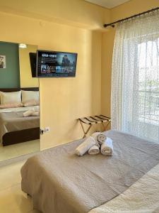 a bedroom with a bed with two towels and a television at FK Maison in Agrinio