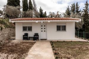 ein kleines weißes Haus mit zwei Stühlen davor in der Unterkunft Olive Grove in Bar