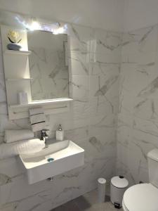 a white bathroom with a sink and a mirror at Digkas Apartments in Kato Korakiana