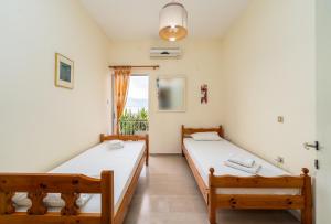two beds in a room with a window at Sainis Rooms in Selianitika