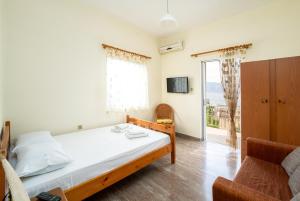 a bedroom with a bed and a chair and a window at Sainis Rooms in Selianitika