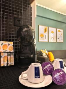 a black coffee maker sitting on a counter with purple cups at FK Maison in Agrinio