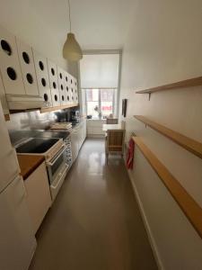 a kitchen with white cabinets and a long hallway at Home Inn LNG20 in Stockholm