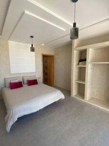 a bedroom with a large white bed with red pillows at Ezz’Dar HOME II in Asilah