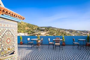 eine Terrasse mit Tischen und Stühlen an einer blauen Wand in der Unterkunft Dar MD in Chefchaouen