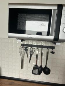 a shelf with forks and spoons and a microwave at MR Ferienwohnung - Wohnung Mary in Barsinghausen