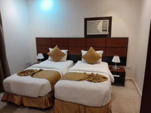 two beds in a hotel room with white sheets at لجين الجوهرة للوحدات المخدومة in Al ‘Azīzīyah