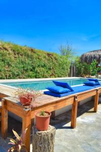 una piscina con almohadas azules en un banco de madera en Casa Lodge (primera fila) en Vichayito