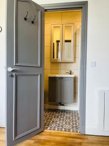 La salle de bains est pourvue d'un lavabo et d'une porte. dans l'établissement Appartement cosy bord de mer, à Port-en-Bessin-Huppain